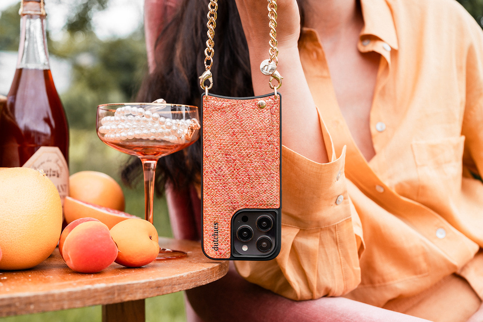 A stylish individual holding a phone case from the Pandora collection with fruity drinks and vibrant colors.
