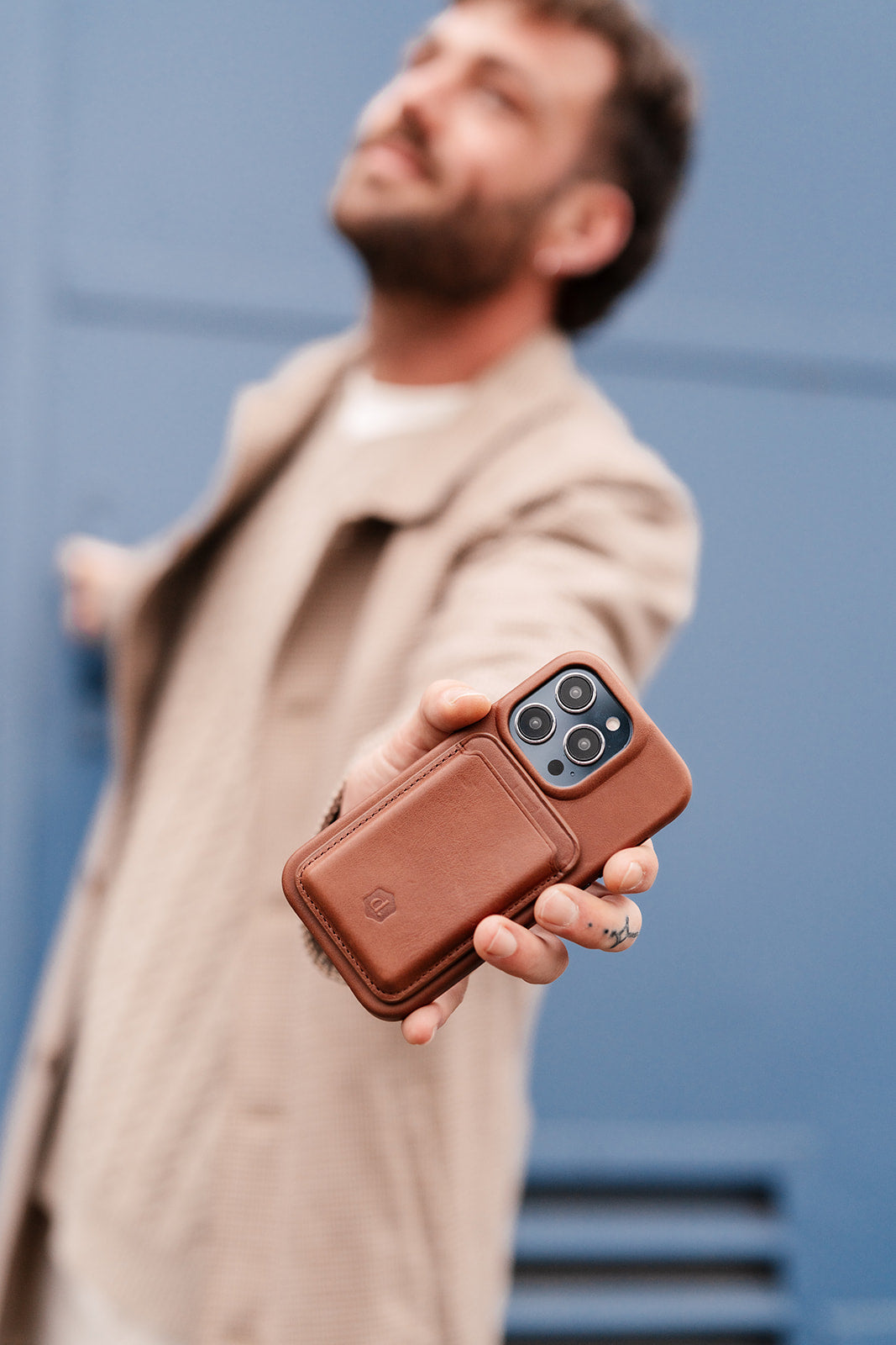 A stylish man showcasing a brown phone case from the Dutchies Men collection.