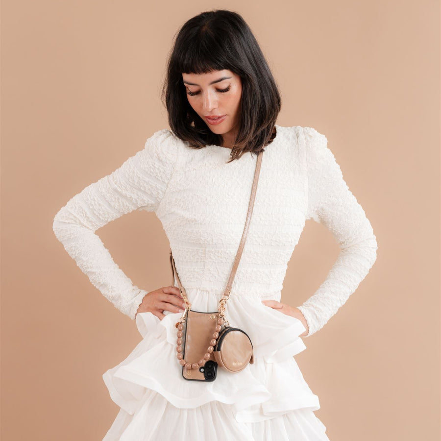Stylish model wearing white dress with cappuccino colored bag showcasing fashion elegance.
