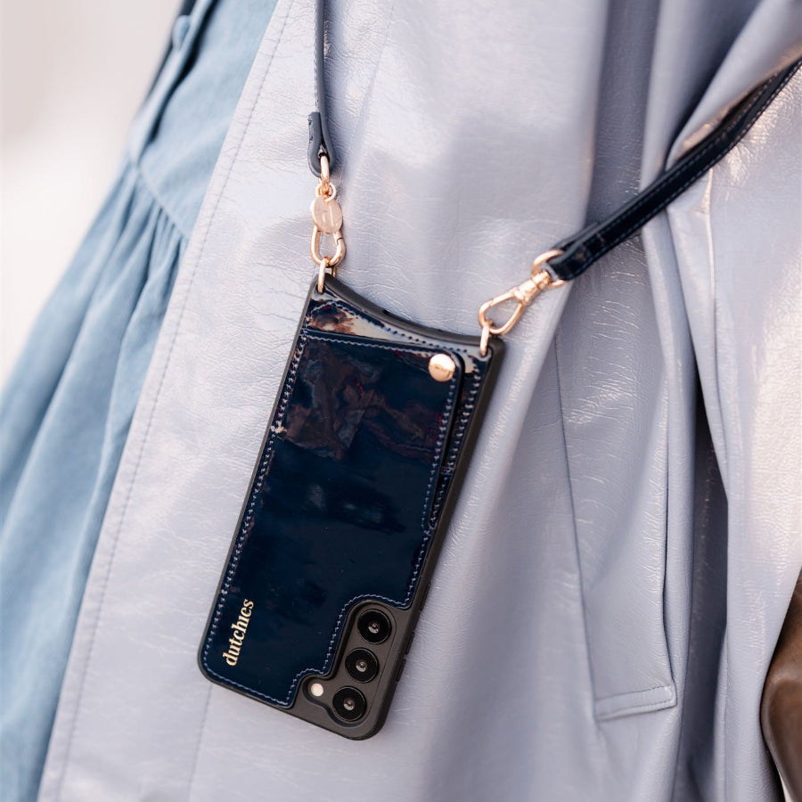 Stylish Samsung Case + Strap hanging from a shoulder, featuring a glossy navy finish and chic design.