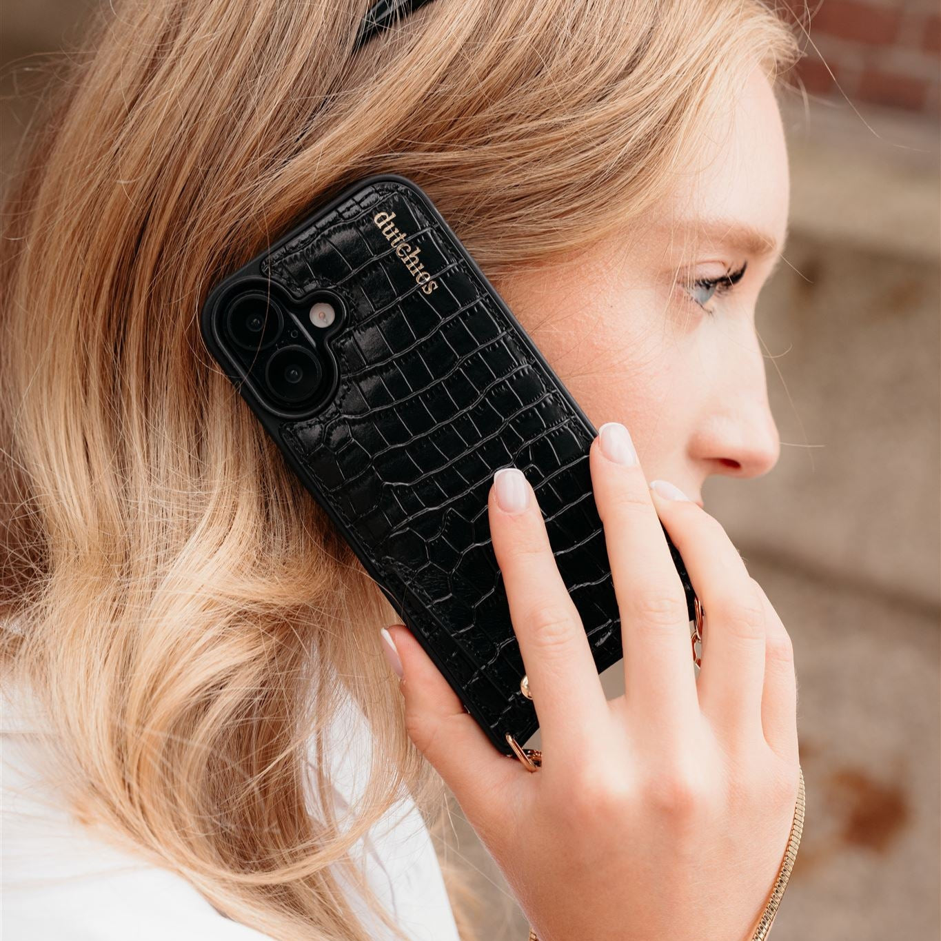 Woman holding a phone with a stylish black case in a textured design, showcasing Black Cases + Straps.