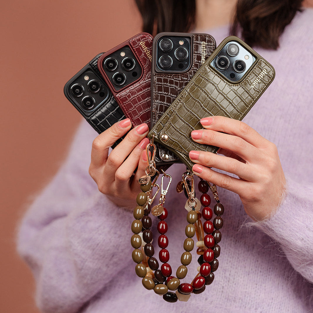 Woman in pink top showcasing phone cases from the Crocodile Chic collection while sitting stylishly.