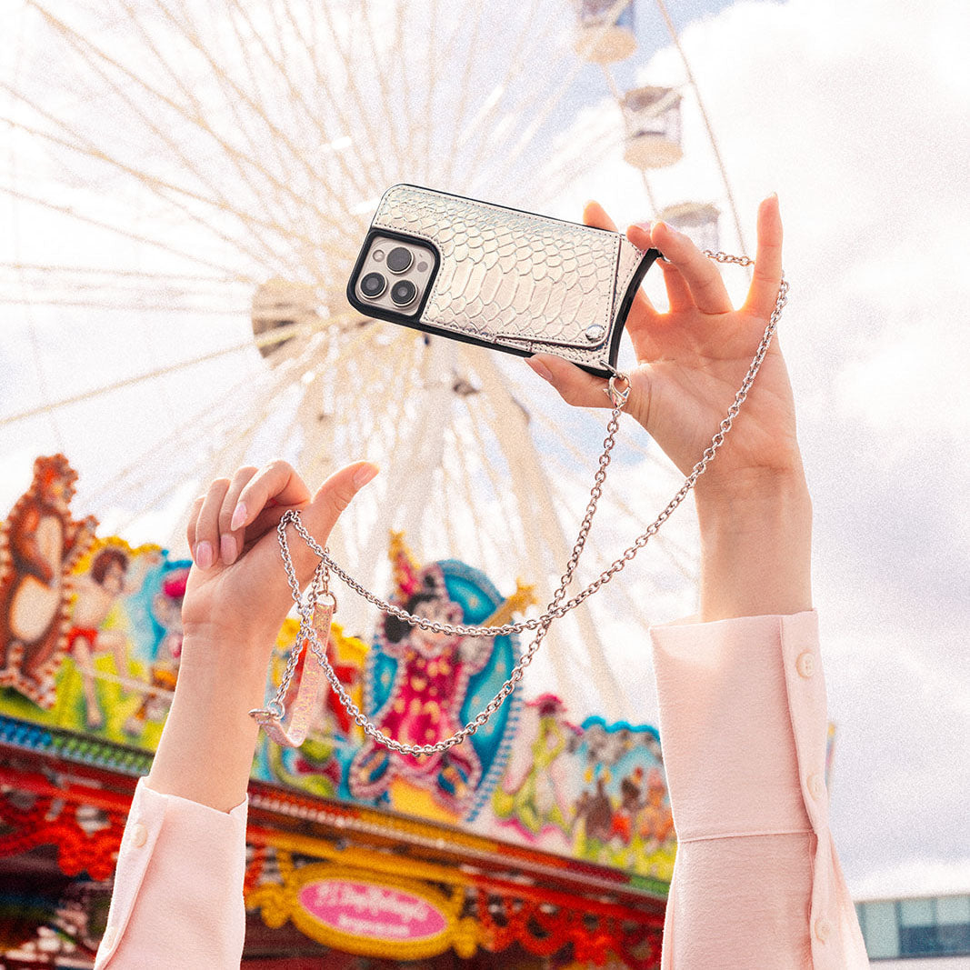 Person holding a stylish phone case with a chain at a festival, perfect for a Festival Outfit.