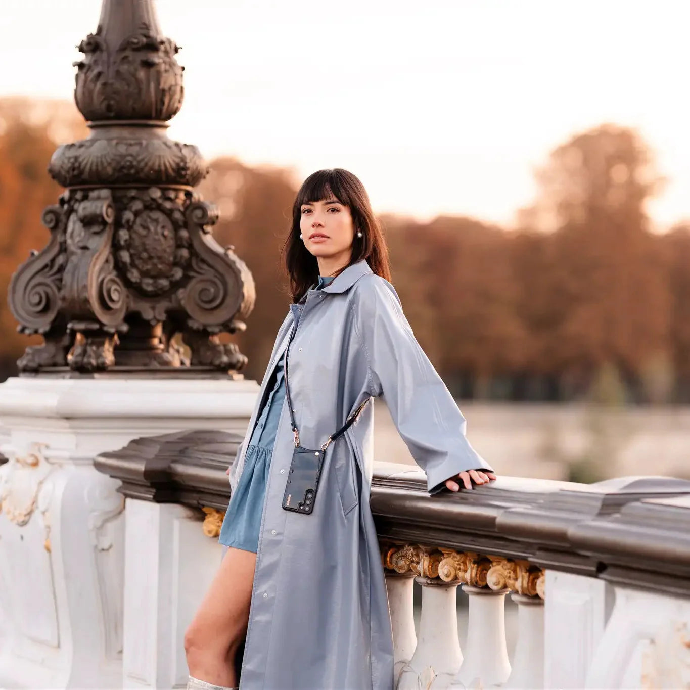 Model in navy gloss coat by a railing, showcasing the Navy Gloss collection in a stylish outdoor setting.