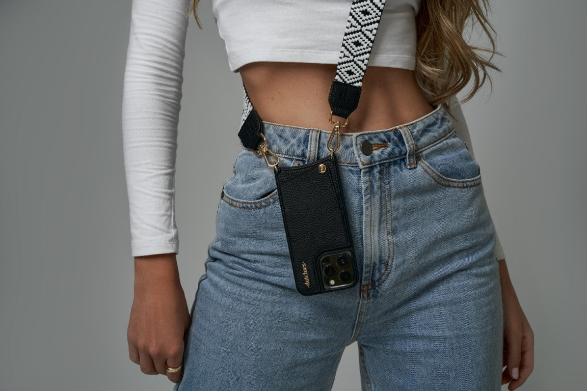 Stylish woman wearing an iPhone 15 Case with a strap, showcasing modern fashion and functionality.