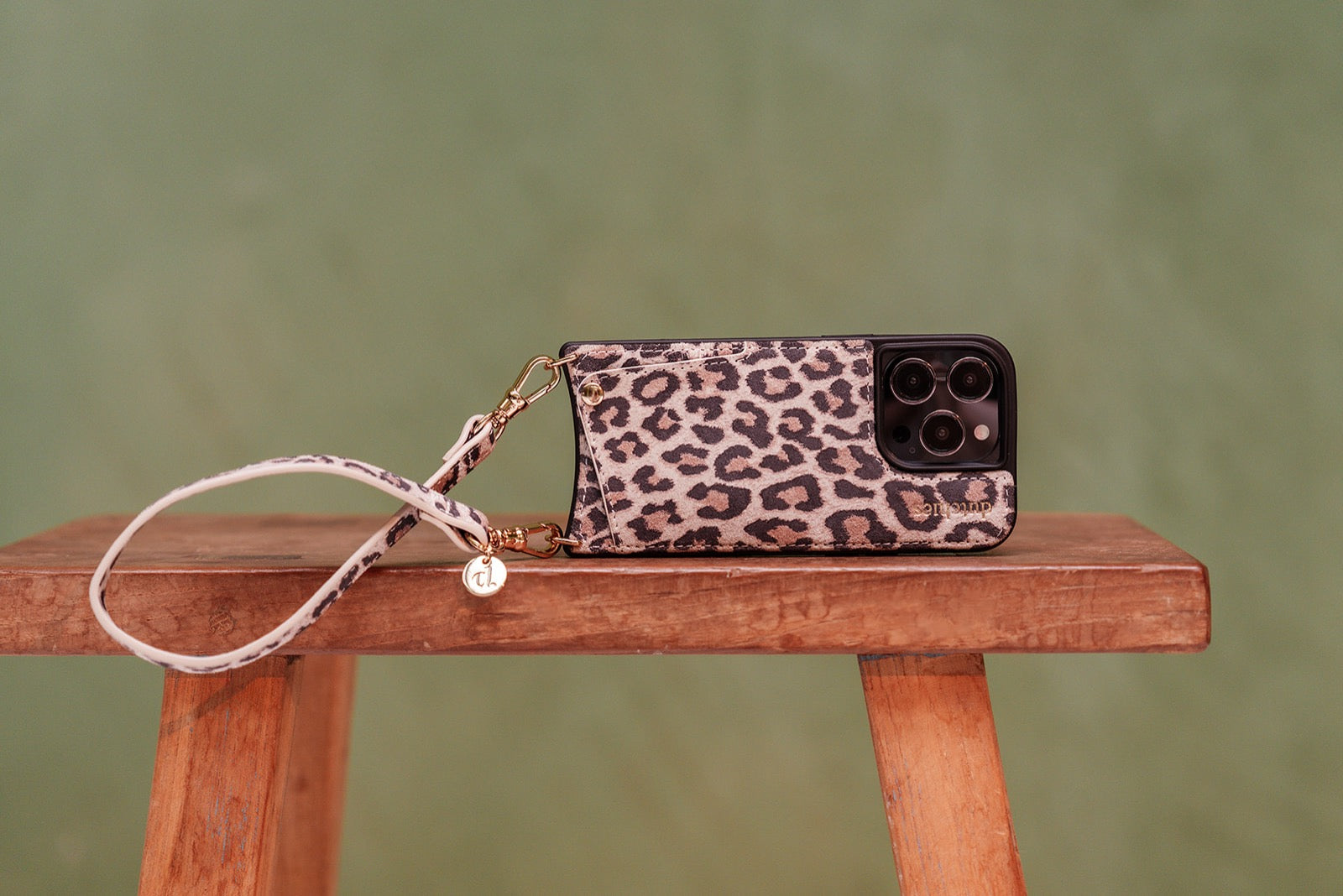 Stylish leopard print case for iPhone 16 PRO MAX with phone chain and charms on wooden table.