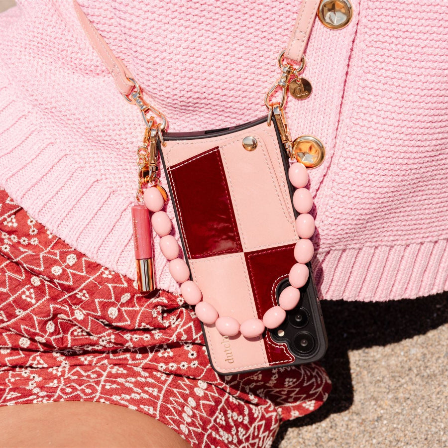 Stylish pink phone charm on a phone case, enhancing the look with high-quality beads, set against a casual outfit.