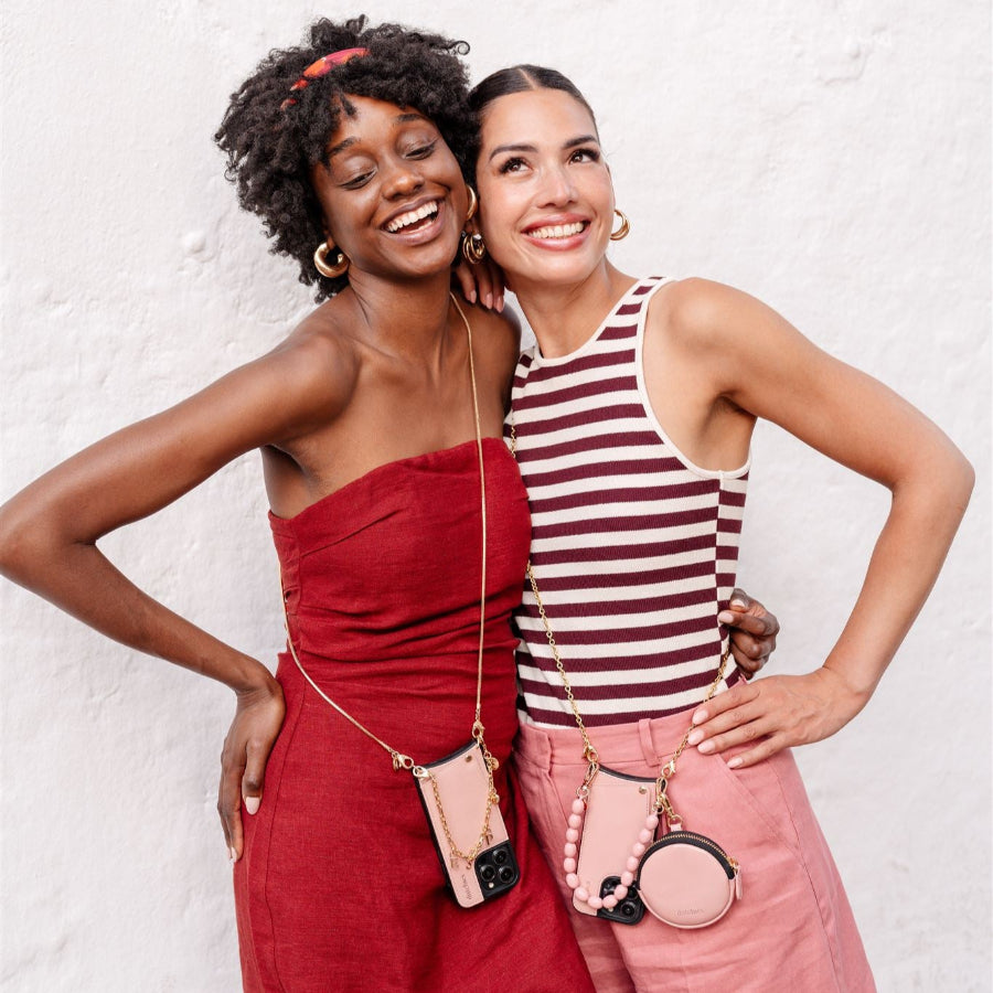 Two women smiling, showcasing pink phone charms styled with their outfits, embodying confidence and elegance.