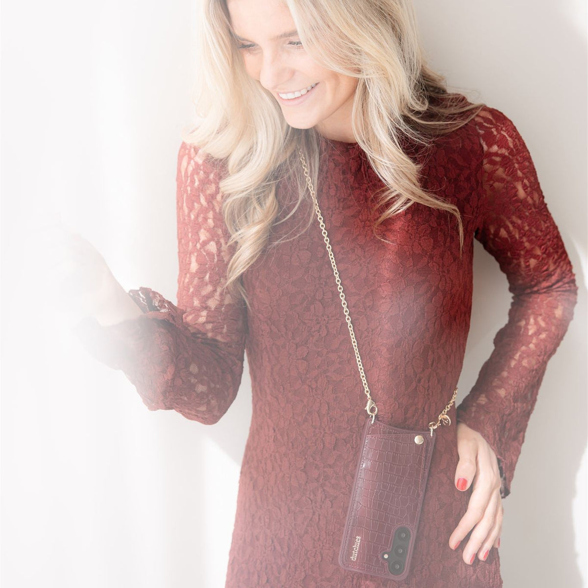 Woman in burgundy dress holding phone with Spanish Chain Set | Samsung | Burgundy, stylish and convenient.