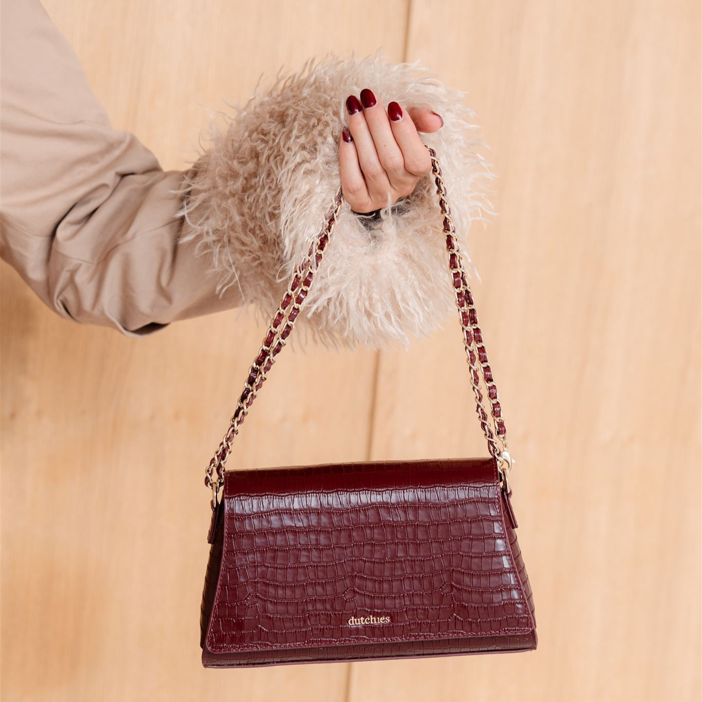 Sophie Crossbody Bag | Burgundy styled with a chic outfit against a warm wooden backdrop, showcasing its elegant design.