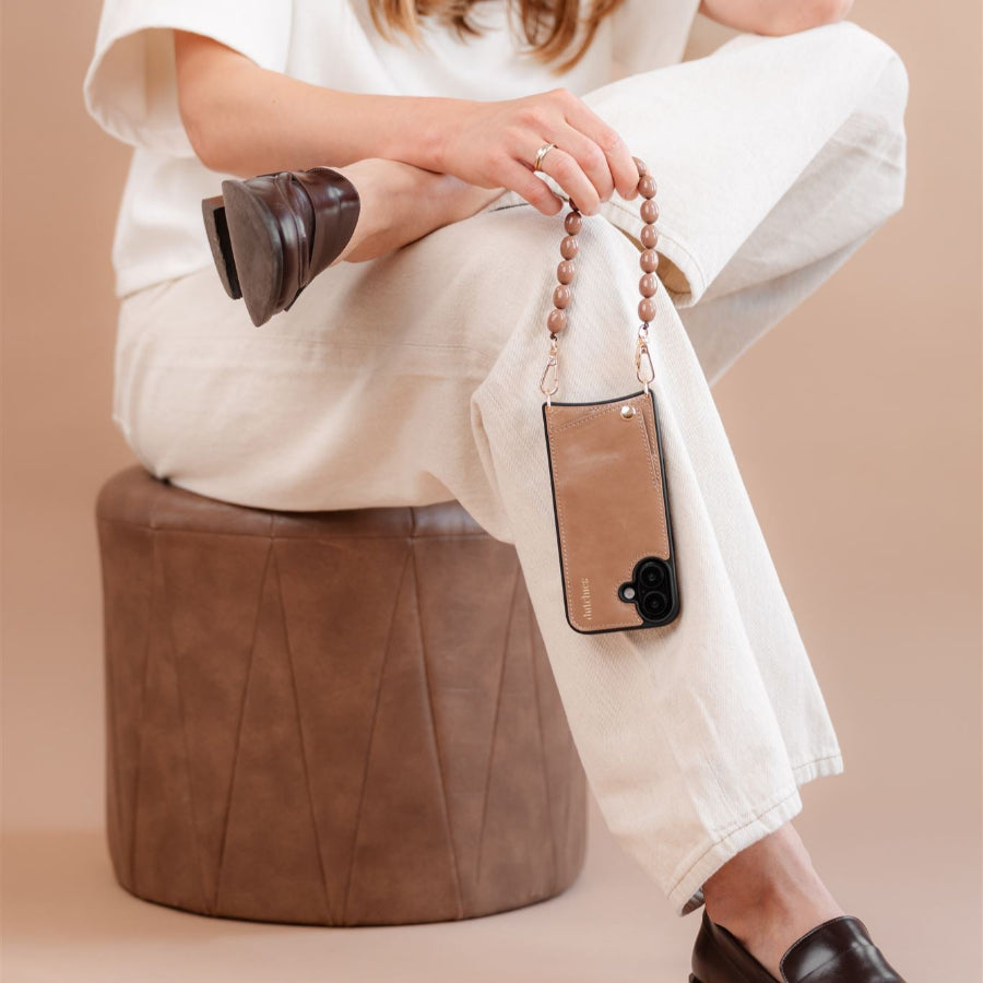 Stylish woman holding a Rachel phone charm strap with a modern phone, showcasing contemporary fashion.