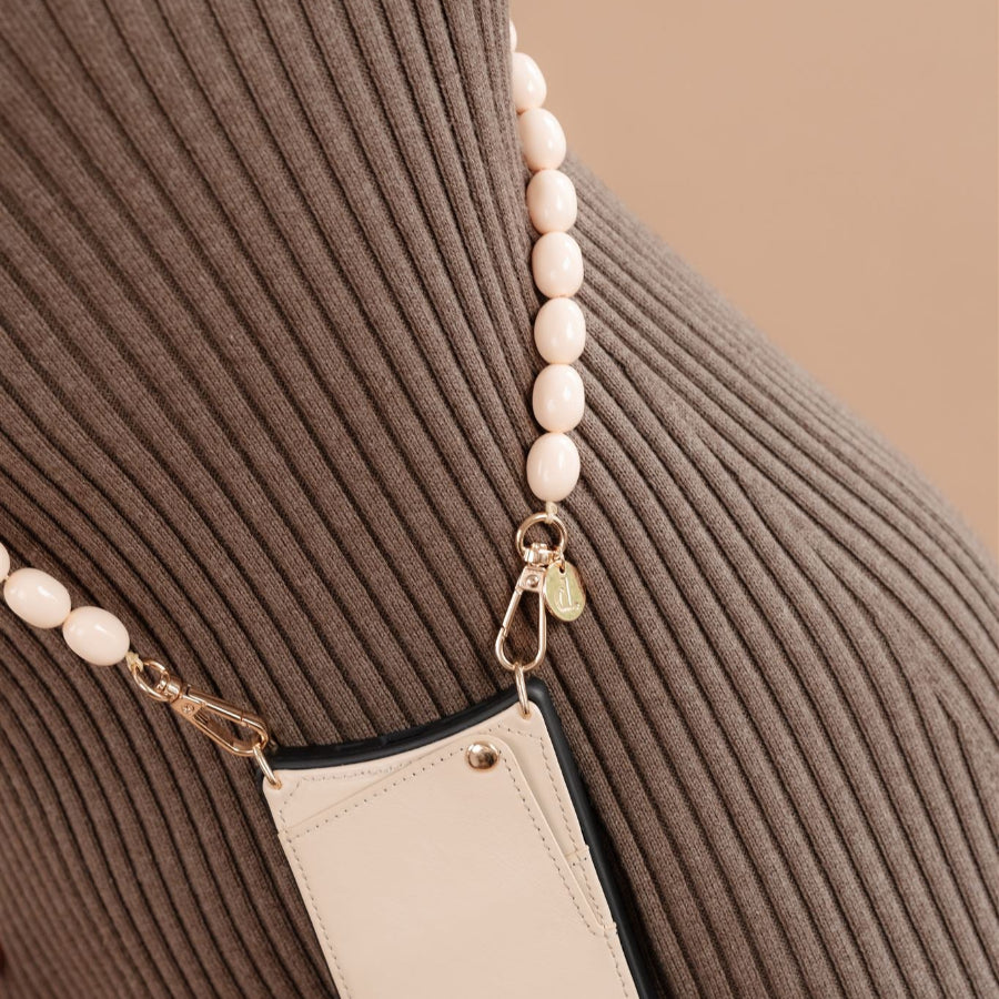 Beaded phone chain Gwen styled on a textured surface, showcasing its elegant design and soft color palette.
