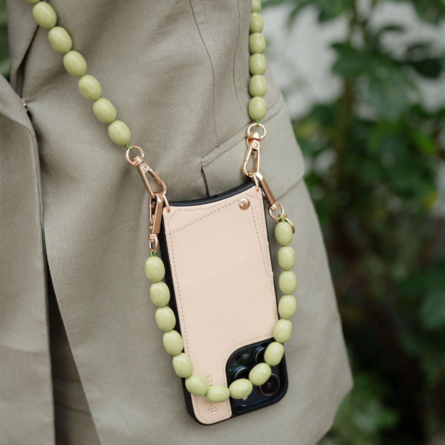 Beaded phone charm featuring a soft green design, elegantly attached to a phone case for stylish convenience.