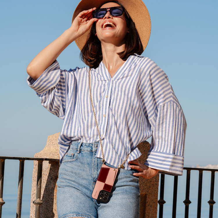Woman in a striped shirt and hat enjoying the outdoors with an iPhone Case | Gloss Lollipop attached to her outfit.
