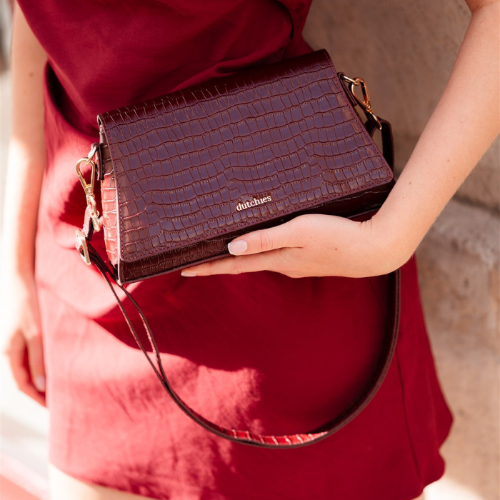 Sophie Crossbody Bag | Burgundy held by a woman in a burgundy outfit, showcasing its elegant design.