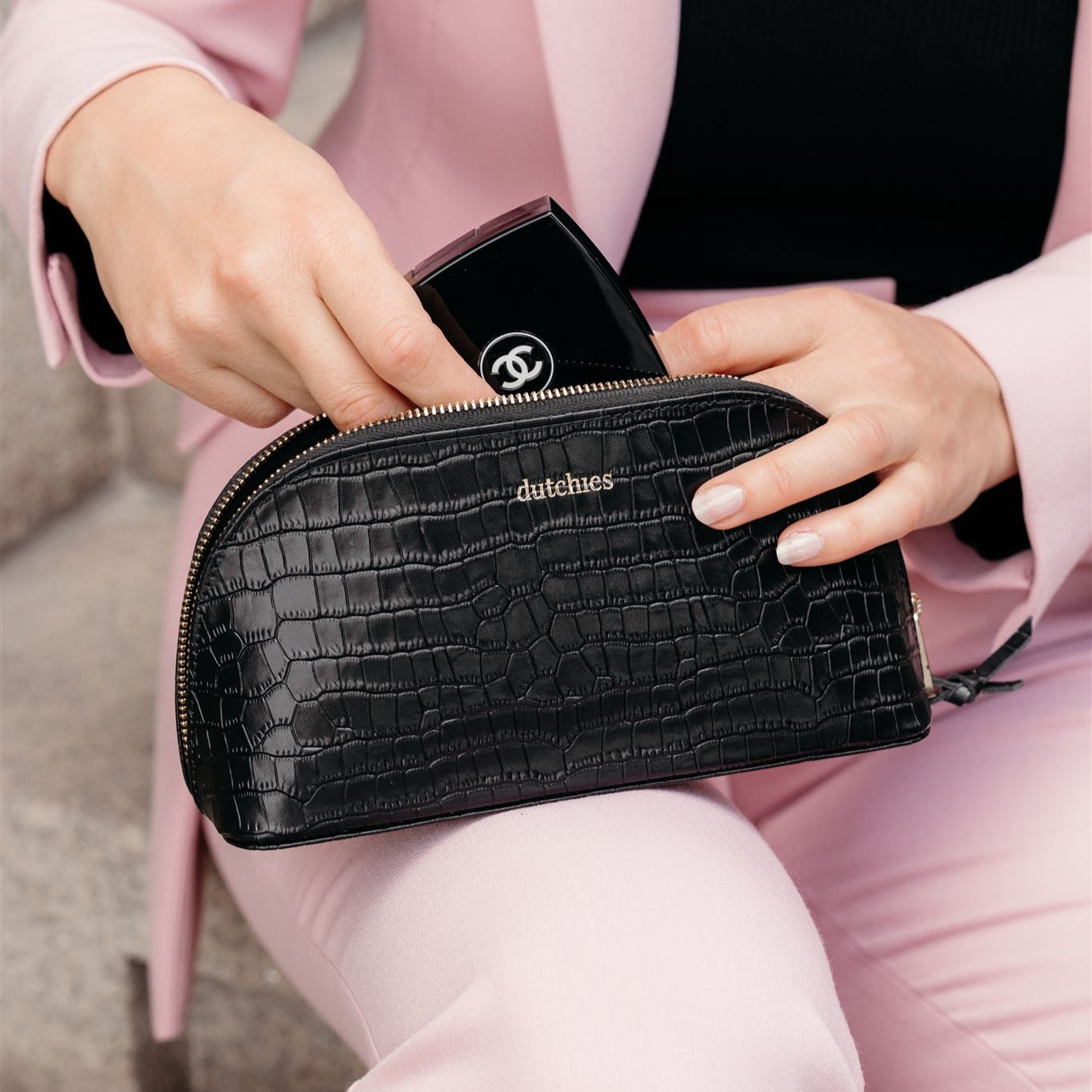 Stylish black leather Pencil Pouch with gold details, perfect for makeup and stationery, held by a woman in a light pink suit.