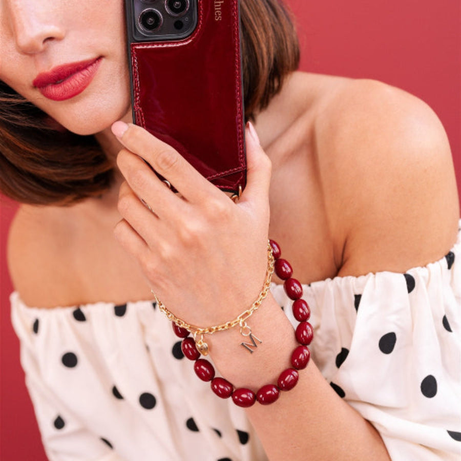 Phone Charm | Beaded | Charley shown on a person holding a smartphone with a red beaded phone charm.
