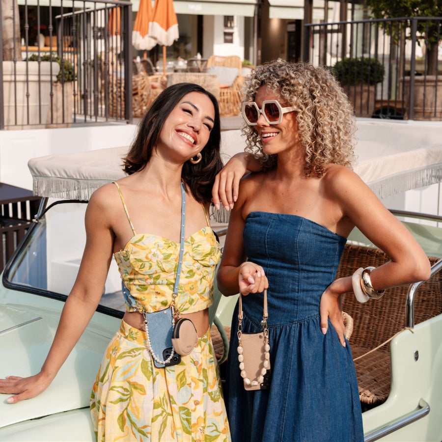 Two stylish women smiling with their Samsung cases with cardholder, enjoying a sunny day outdoors.