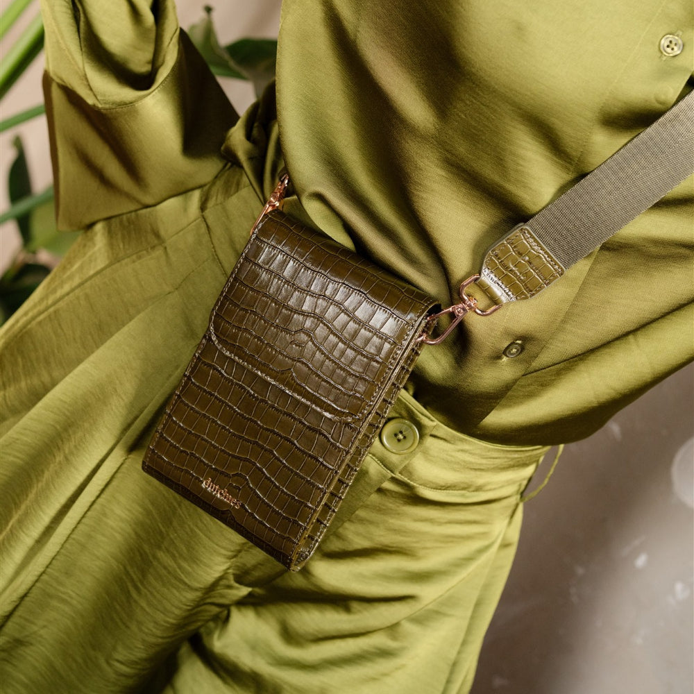 Person wearing a green jacket with a brown crocodile-patterned phone bag over their shoulder.