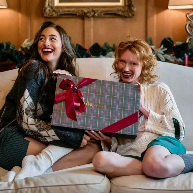 Luxury Box | iPhone Case | Raspberry Red gift set with two smiling women unwrapping on a cozy sofa.