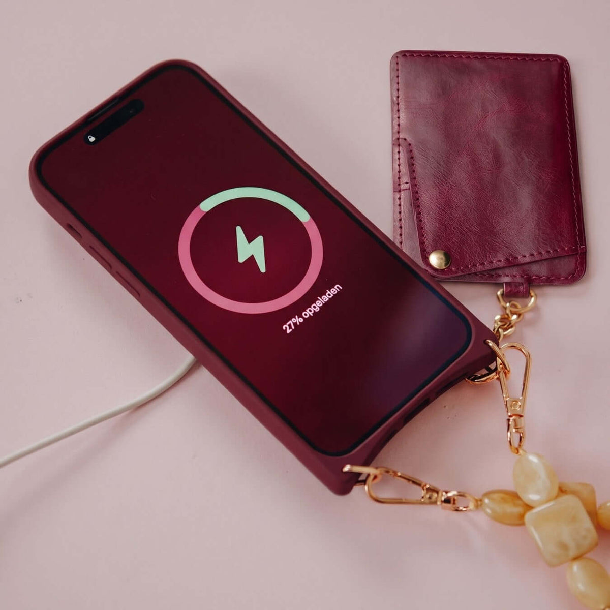 Raspberry red leather MagSafe iPhone case on a wireless charger.