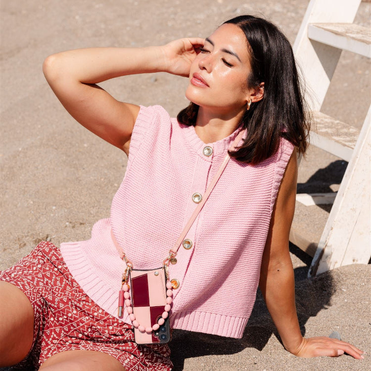 Frau genießt die Sonne am Strand in einem rosa Outfit mit einer Samsung-Hülle | Gloss Lollipop mit Kartenfach.