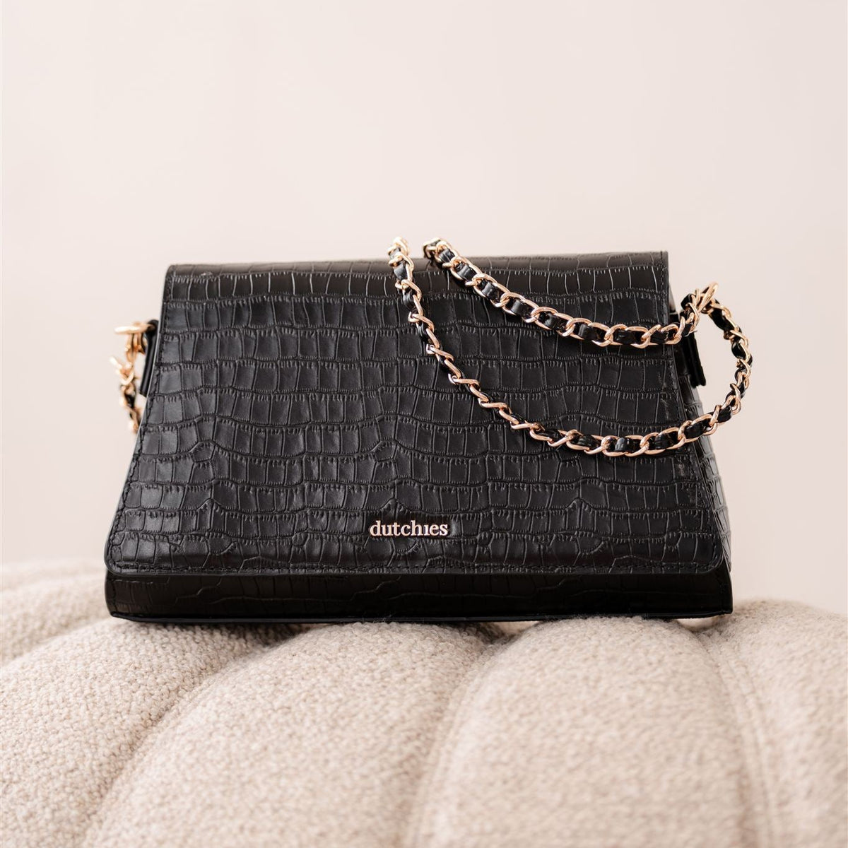 Sophie Crossbody Bag | Noir Gold på en blød overflade, der fremviser det elegante design og den gyldne kæde.