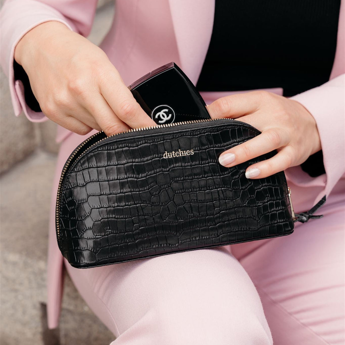 Stylish black leather Pencil Pouch with gold details, perfect for makeup and stationery, held by a woman in a light pink suit.
