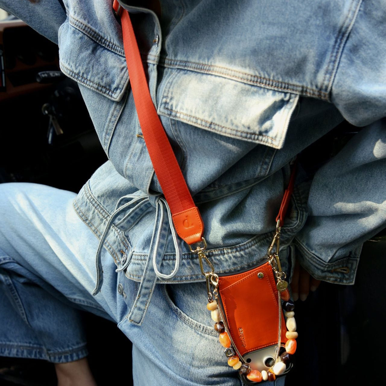 Phone Strap | Basic | Orange worn with a stylish denim outfit, showcasing its functionality and vibrant color.