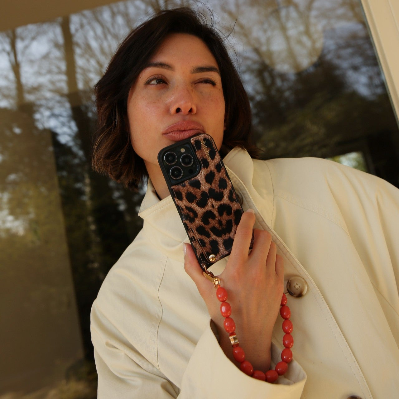 iPhone Case | Leopard held by a woman wearing a stylish coat with a chic phone strap.