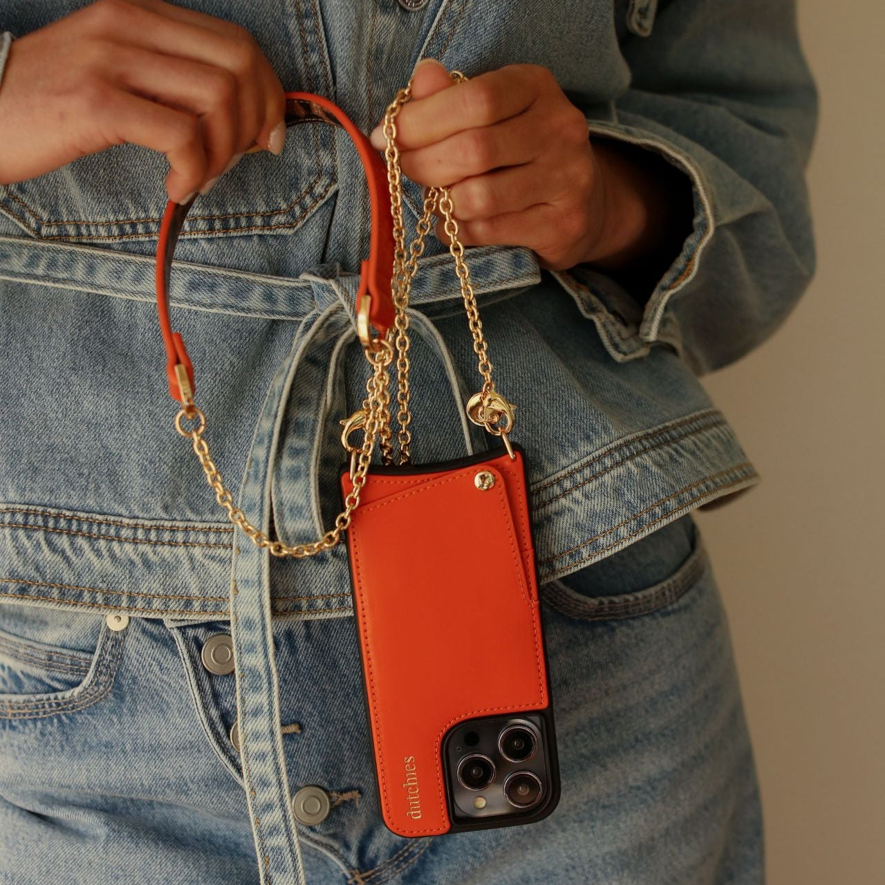 Phone Chain | Spanish | Orange held by a person, showcasing a stylish and practical accessory for busy days.