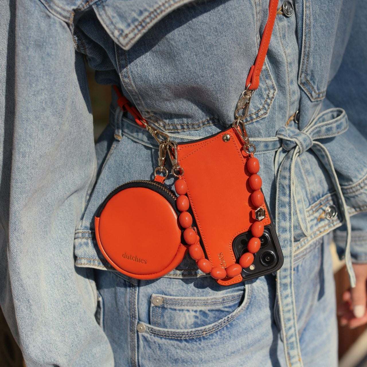 Luxury set | iPhone | Orange accessory with stylish orange phone case and pouch on a denim jacket.