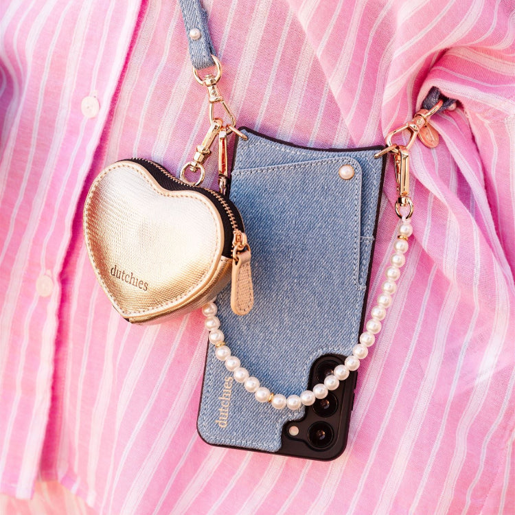 Woman holding a smartphone with a denim case and a drink, styled in a cozy setting.