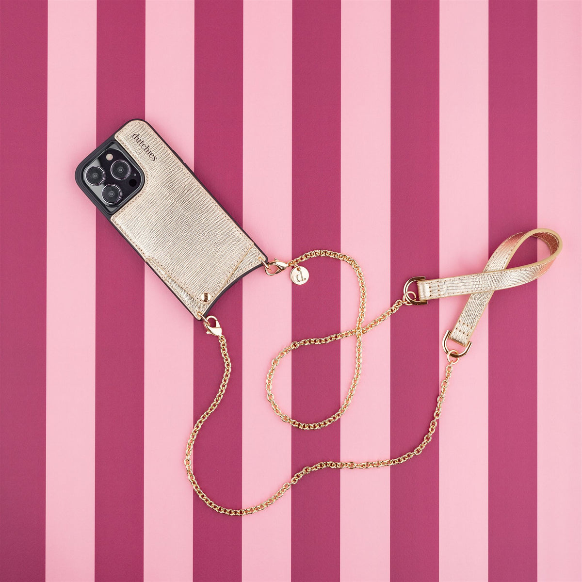Collana per telefono | Spanish | Goldy con una raffinata catena dorata e una custodia chic su uno sfondo a righe rosa.