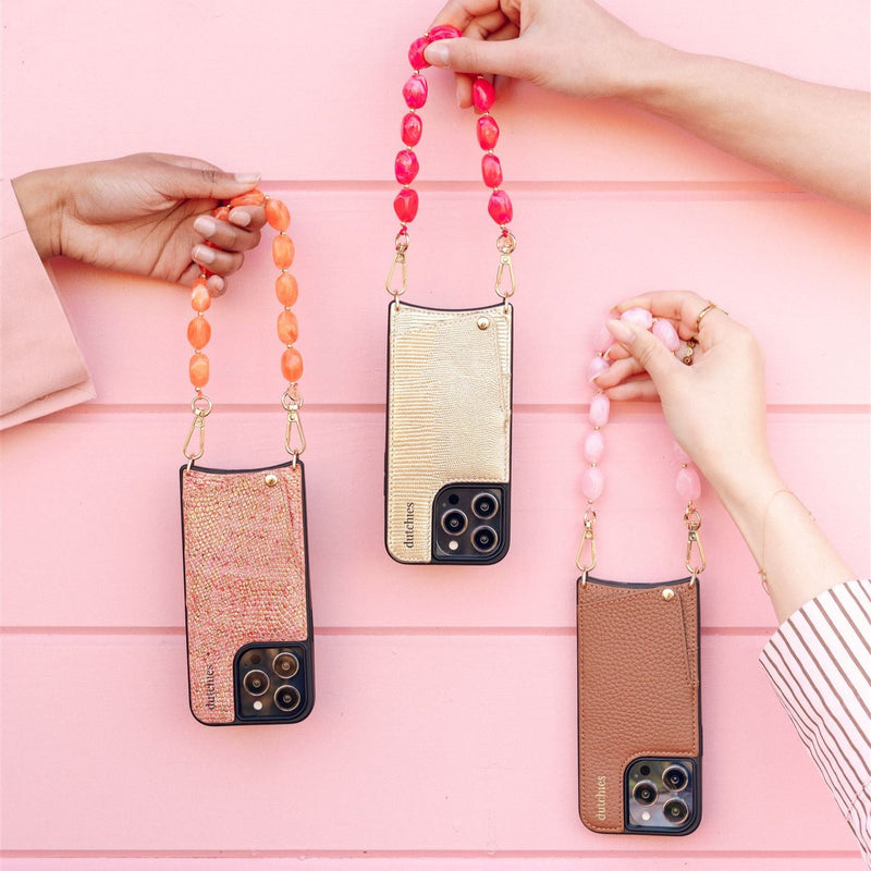 Three stylish phone charms, including the Phone Charm | Beaded | Maxime, in vibrant colors against a pink background.