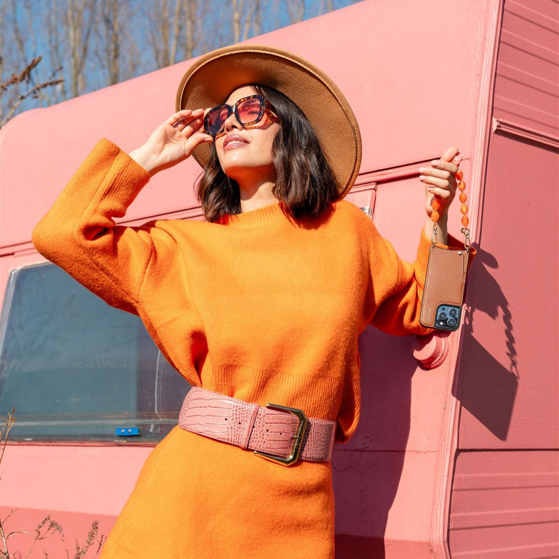 Phone Charm | Beaded | Maxime styled with a bold orange outfit and accessories against a pink backdrop.
