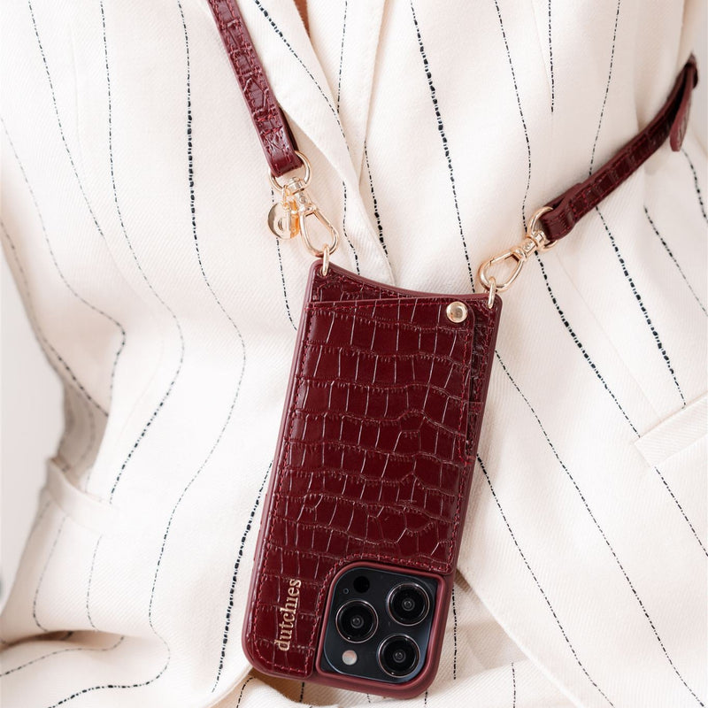Slimline | Strap | Burgundy phone case with cardholder stylishly hanging on a chic outfit for hands-free convenience.