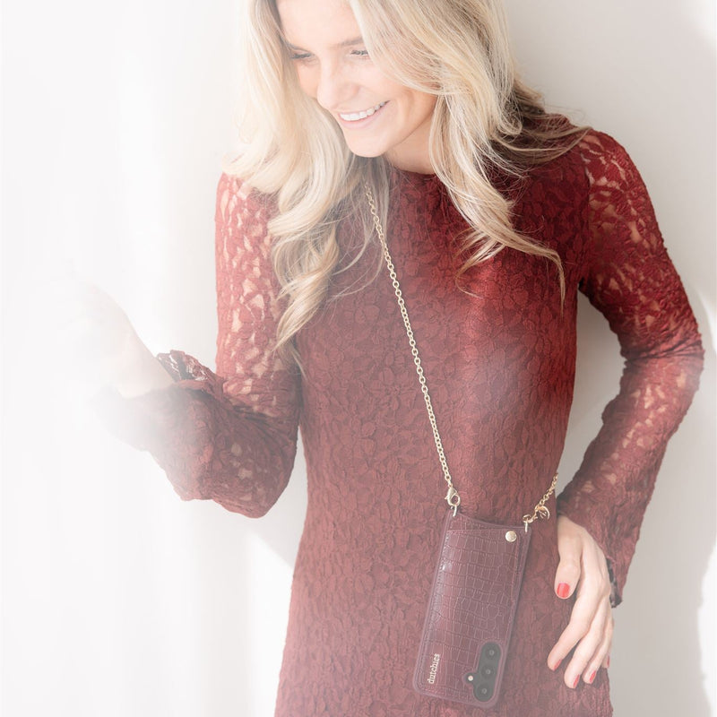 Woman in burgundy dress holding phone with Spanish Chain Set | Samsung | Burgundy, stylish and convenient.