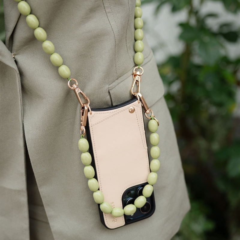 Beaded phone charm featuring a soft green design, elegantly attached to a phone case for stylish convenience.