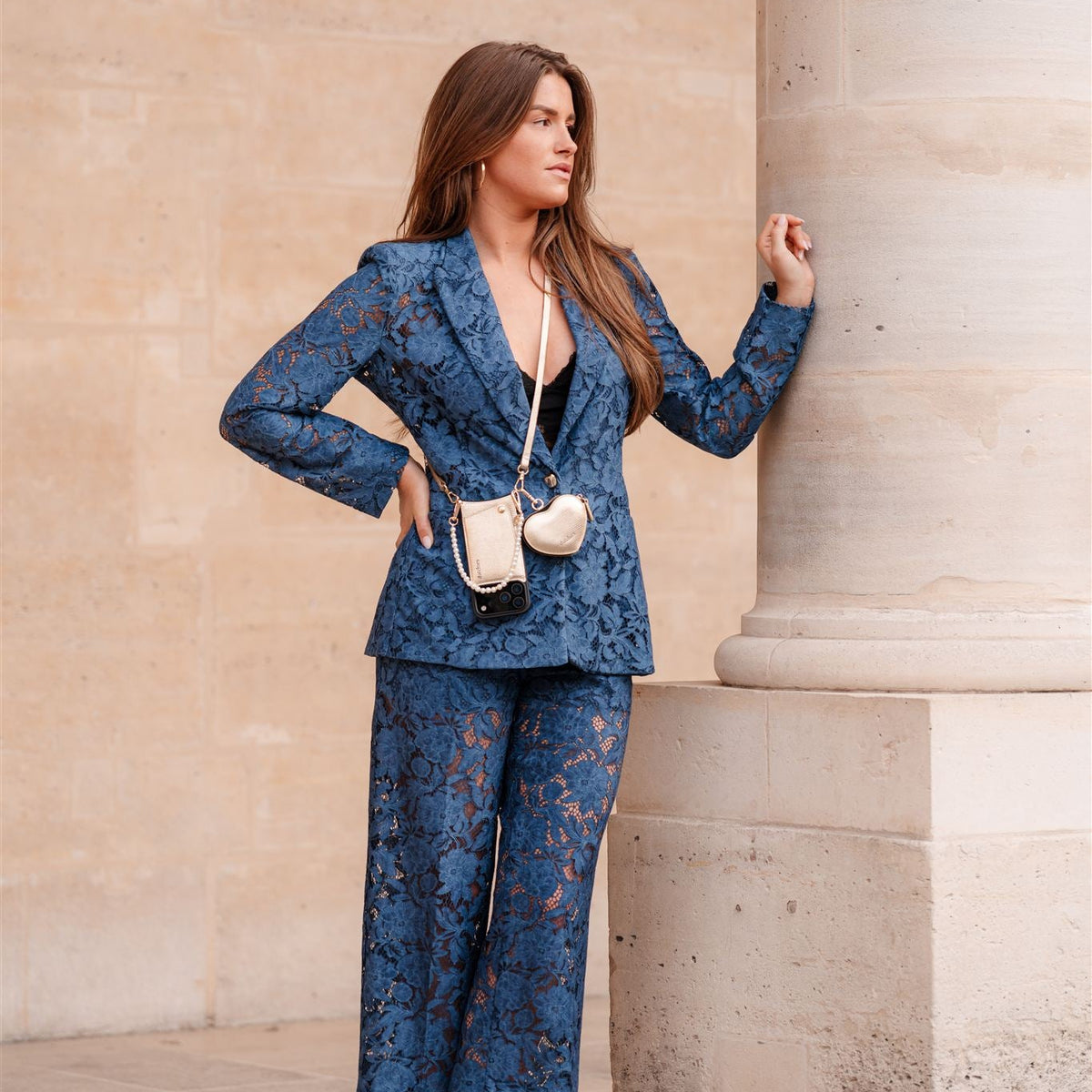 Woman in blue lace suit posing by a pillar with a stylish phone pouch from the Luxury Set | iPhone | Goldy.