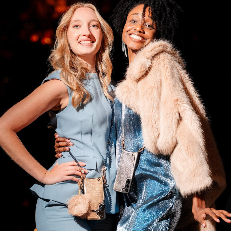 Two women showcasing stylish phone chains, one in a blue dress and the other in a furry jacket, smiling brightly.