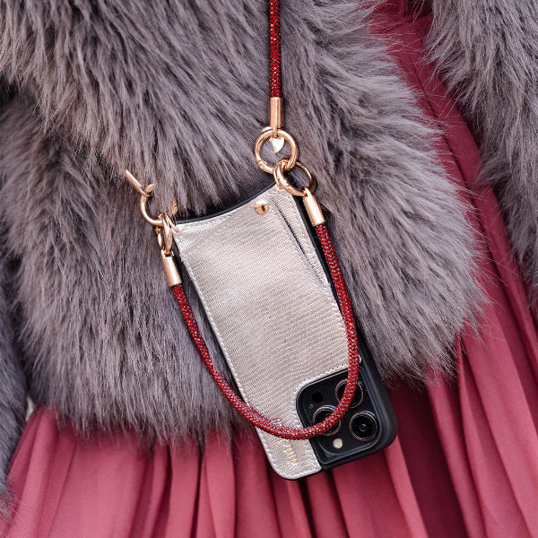 Phone case with red strap held by a person wearing a fur coat