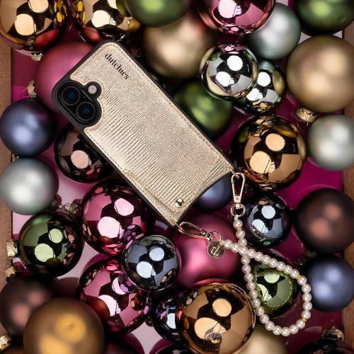 Phone case surrounded by colorful Christmas ornaments on a pink background