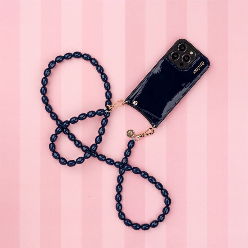 Phone Chain | Beaded | Georgia in navy with a stylish crossbody strap on a pink striped background.