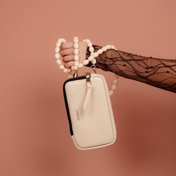 Phone Bag Rose | Vanilla held with a stylish bead strap against a soft pink background.