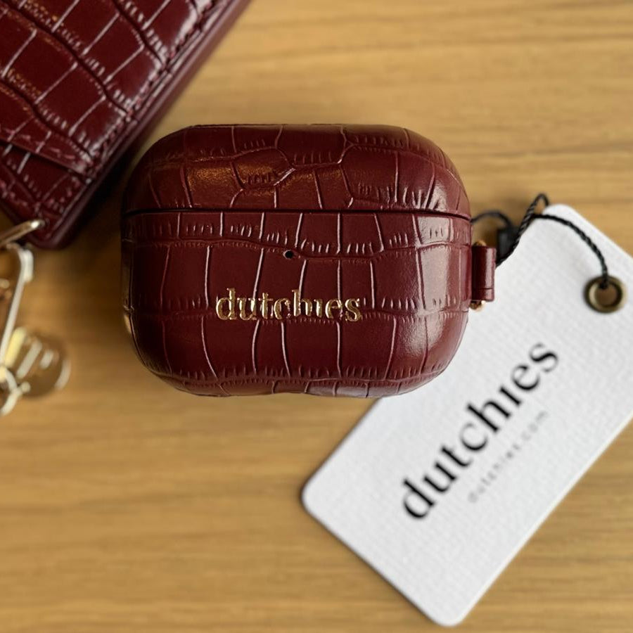 Brown crocodile-patterned airpod case with 'dutchies' tag on a wooden surface