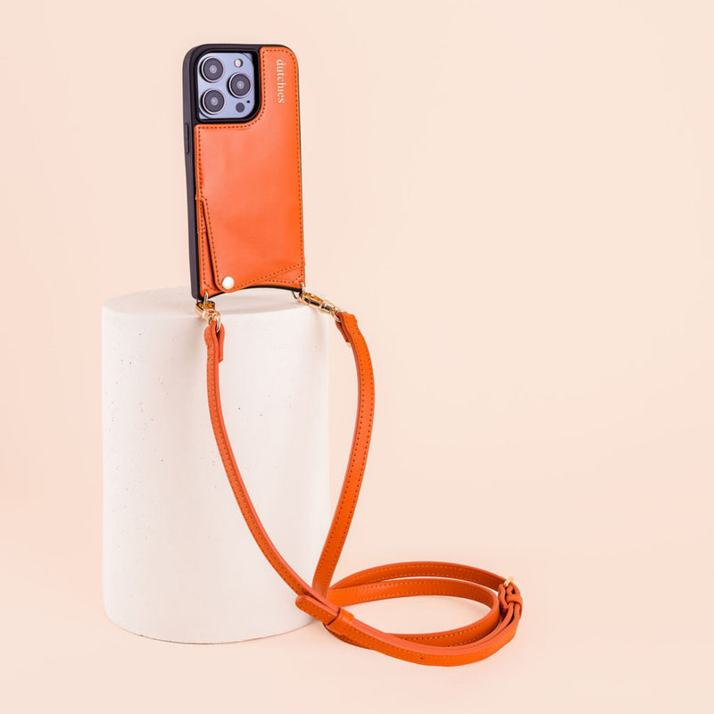 Phone strap | Slimline | Orange attached to a stylish phone on a pedestal, showcasing its trendy design and practicality.