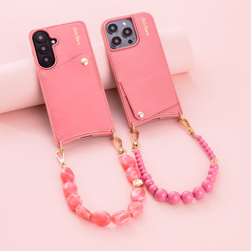 Phone Charm | Beaded | Alexandra, pink phone charm strap elegantly displayed next to mobile cases on a pink background.