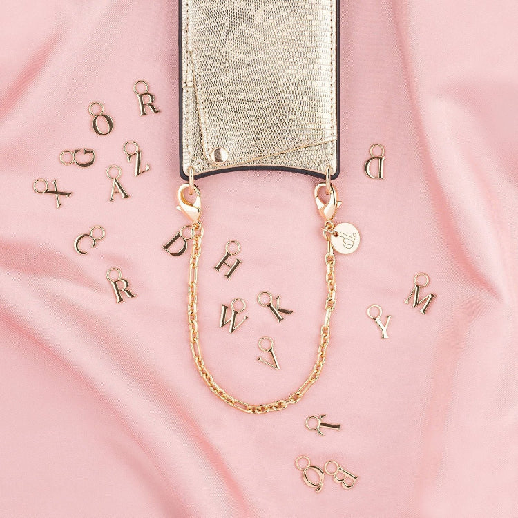 Phone Charm | Gold | Dutch Bandolier with initials and gold chain on pink fabric background.