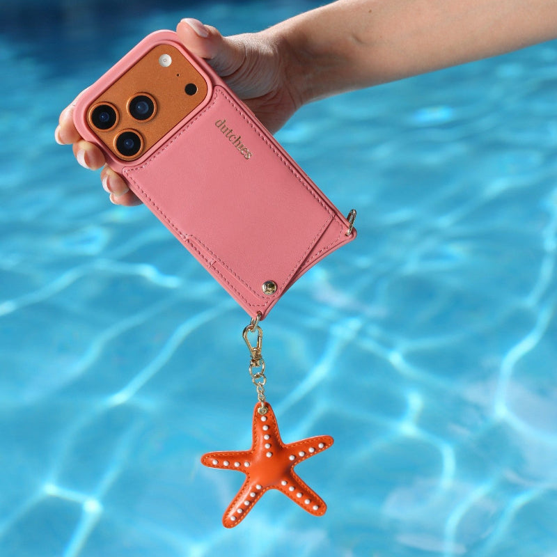 Keychain | Starfish | Orange attached to a pink phone case by the pool.